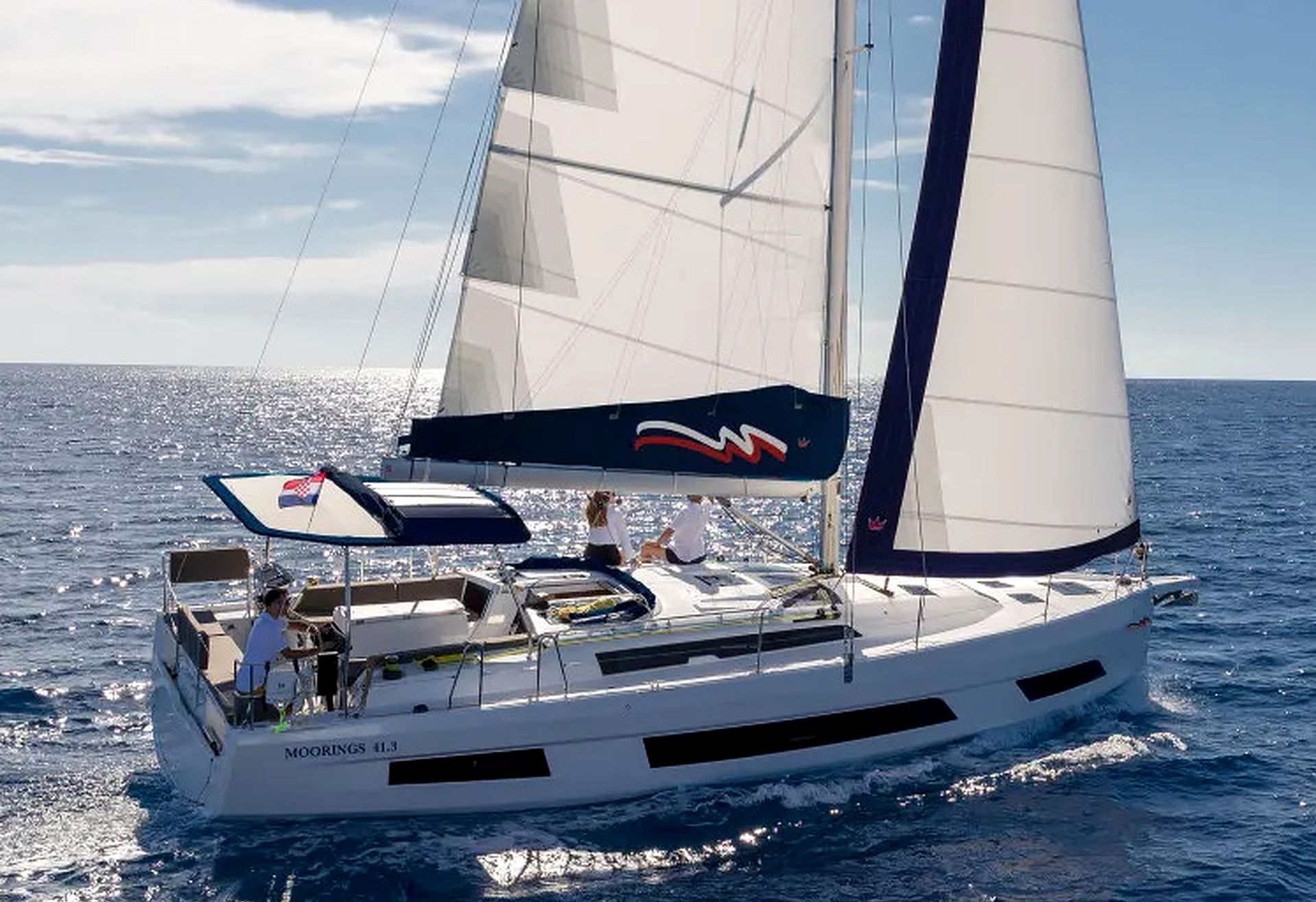 Un velero con casco blanco y un logo azul y rojo en la vela.