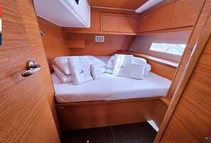 A compact cabin with a bed, a small window, and wooden cabinetry.