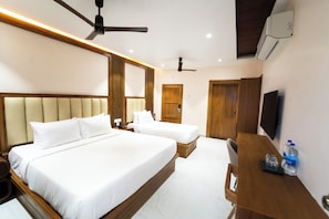 Une chambre dâhĂŽtel avec deux lits, un bureau avec une bouteille dâeau et une tĂ©lĂ©vision.
