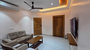 Una sala de estar moderna con un conjunto de sofá, una mesa de centro, un ventilador de techo y un televisor montado en la pared.
