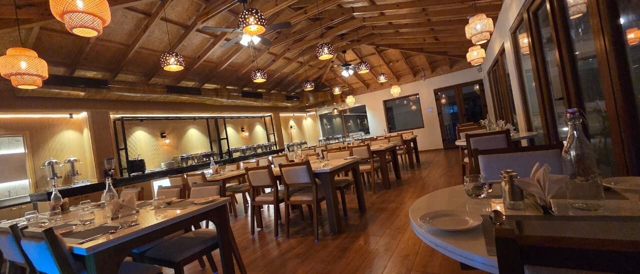 Un restaurant avec un plafond en bois, des tables dressées et des lampes suspendues.