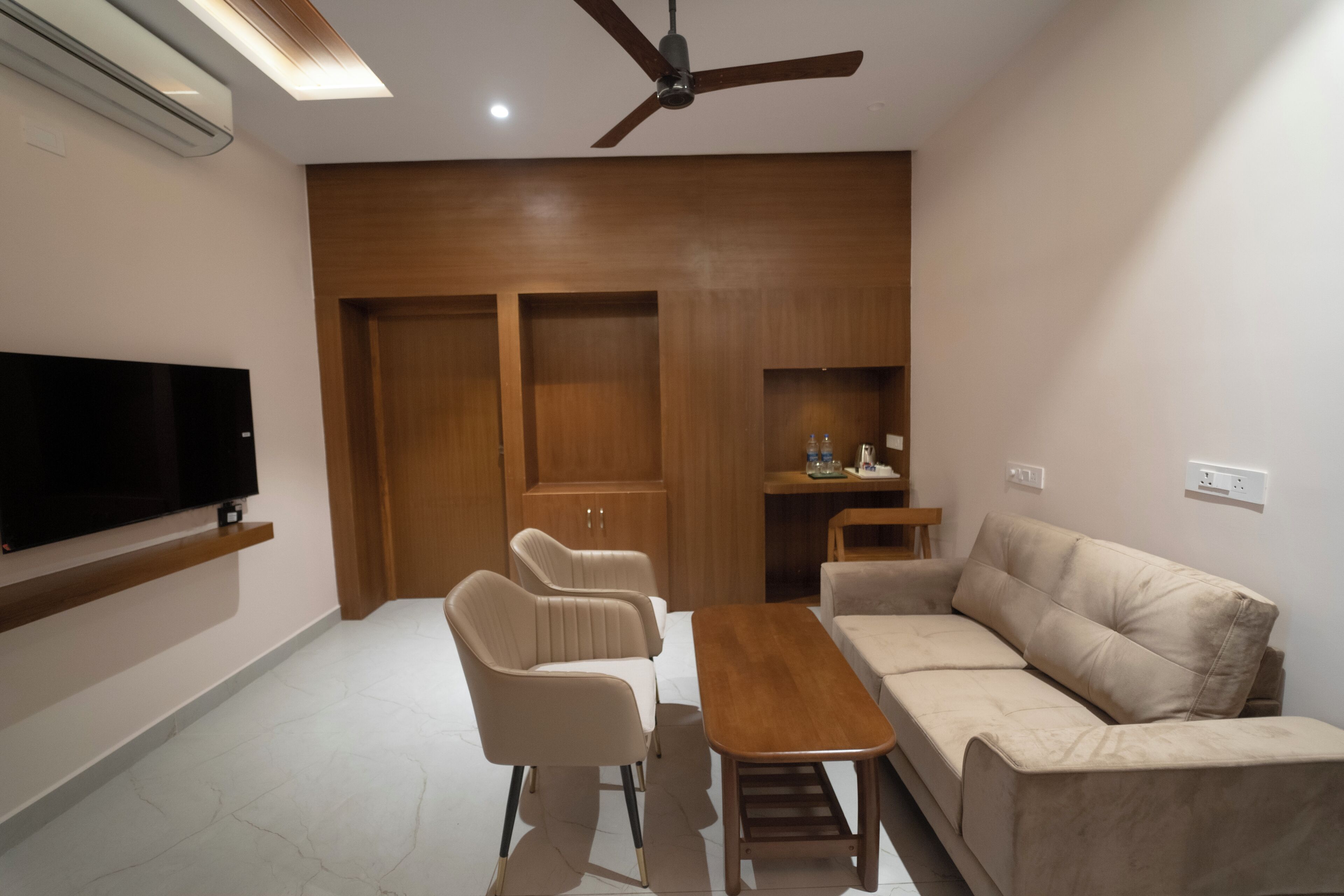 Ein modernes Wohnzimmer mit Flachbildfernseher, Deckenventilator, Holzschränken, einer Couch und einem Couchtisch.