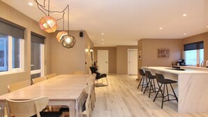 Una cocina moderna con comedor, suelo de madera e iluminación colgante.