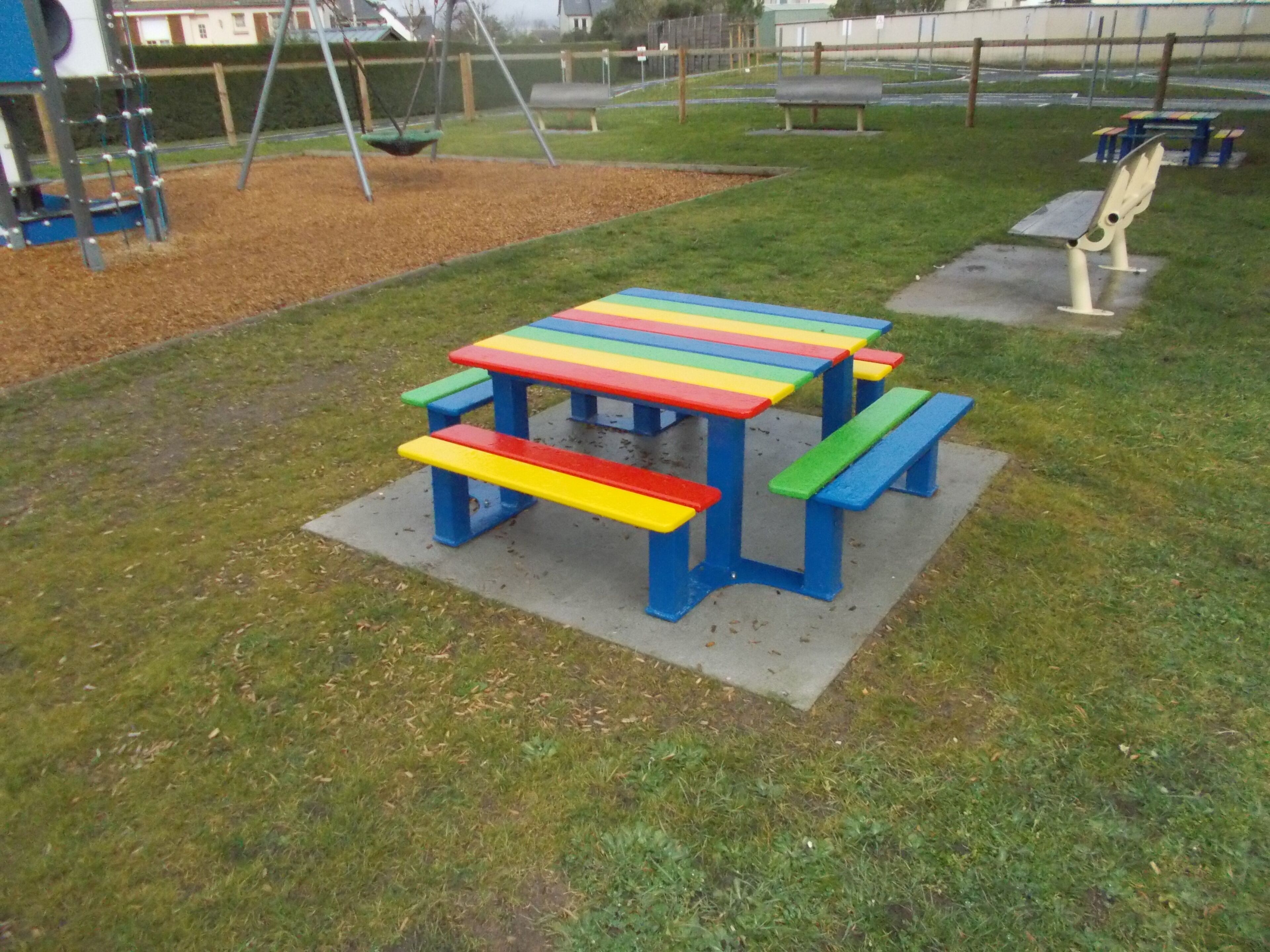Una mesa de picnic colorida con bancos en un parque.