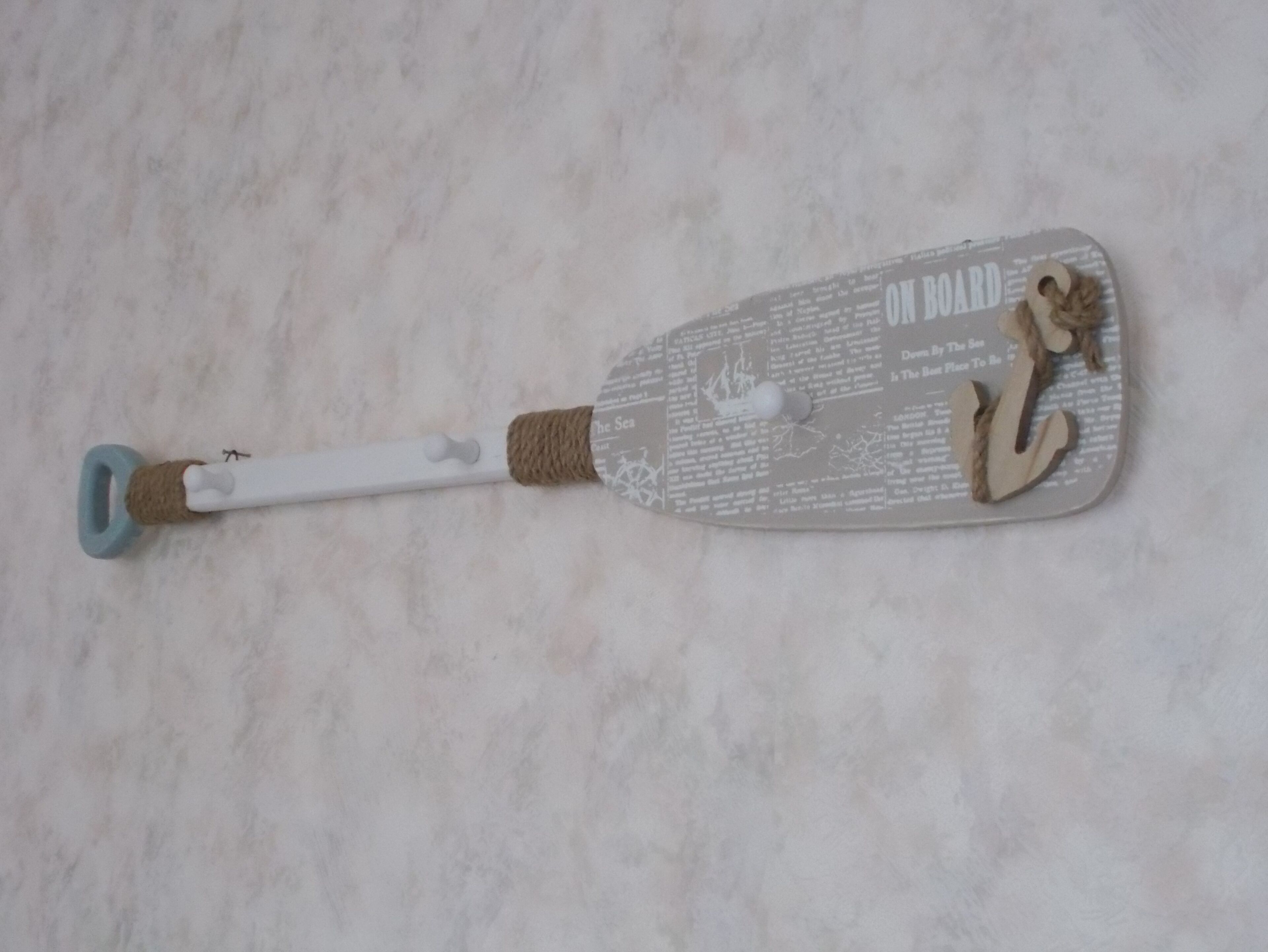 A white cleaning tool with a blue handle and a wooden head, lying on a marble surface.