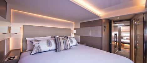 A modern hotel room with a large bed, a skylight, and a view of the adjacent room.