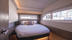A modern interior with a bed, built-in headboard, and large windows.