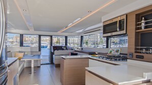 Una cocina moderna con una isla central, electrodomésticos integrados y grandes ventanales con vistas al puerto deportivo y edificios.