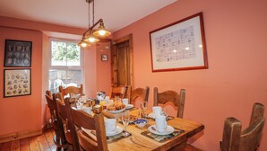 A dining area with wooden chairs, a wooden table, and a hanging light fixture. - Achnagonlin House (Grantown-on-Spey)