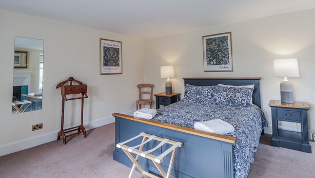 A bedroom with a bed, bedside tables, a mirror, and framed botanical prints on the wall. - Achnagonlin House (Grantown-on-Spey)