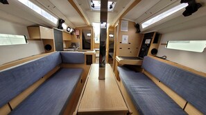 A compact interior with two blue cushioned seating areas, a central table, and a kitchenette with a sink and stove.