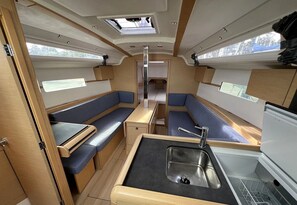A compact RV interior with a kitchenette, seating area, and a central aisle.