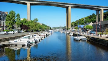 A canal with boats docked, a bridge overhead, and buildings along the water.
