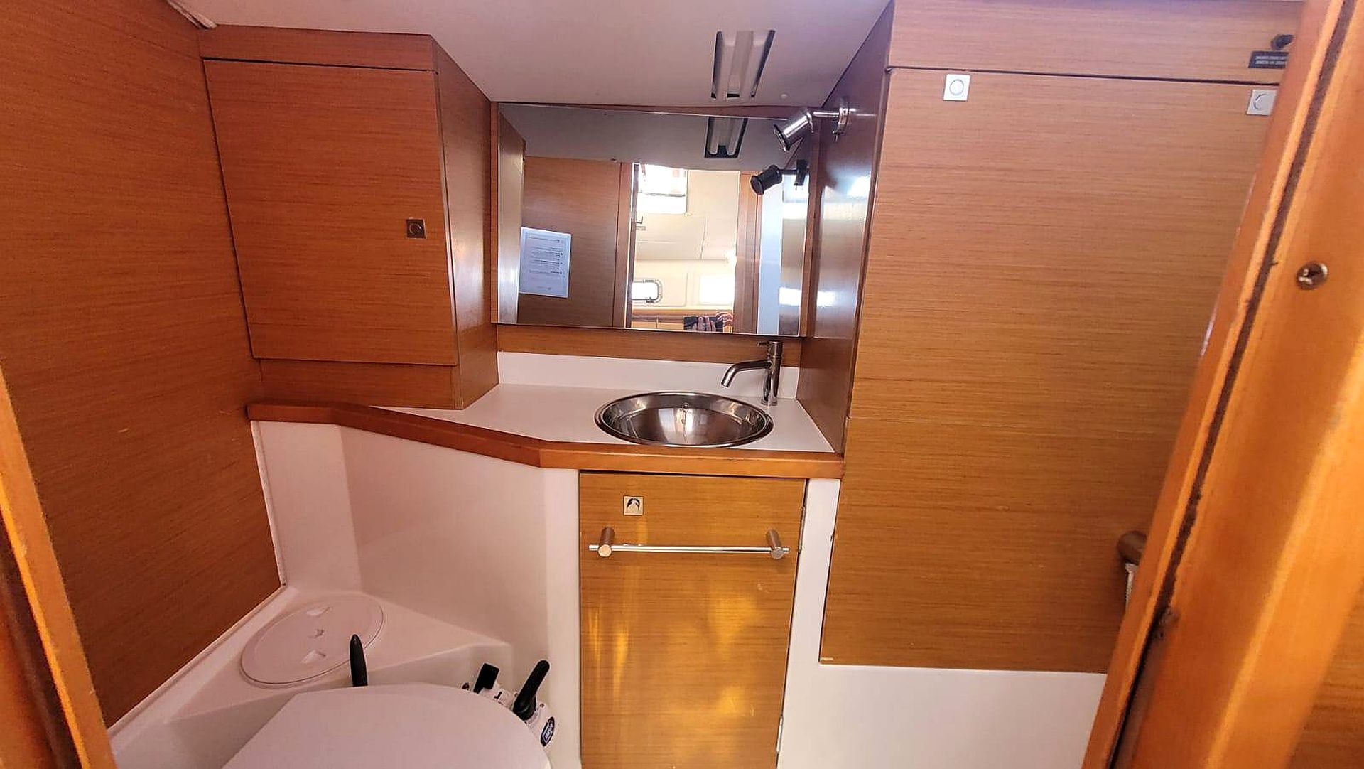 Une petite cuisine équipée comprenant un évier, un petit placard et un miroir.