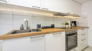 A modern kitchen with white cabinetry, a wooden countertop, a stainless steel sink, a built-in oven, and a coffee maker. - Vacation apartment close to the beach in a quiet location in Crikvenica-Dramalj (Dramalj)