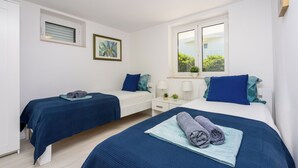 A bedroom with two beds, a window, a bedside table with a lamp, and a painting on the wall. - Vacation apartment close to the beach in a quiet location in Crikvenica-Dramalj (Dramalj)