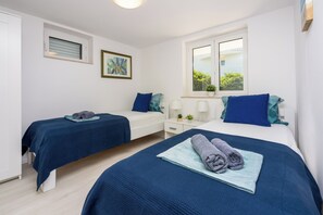 A bedroom with two beds, a window, a bedside table with a lamp, and a painting on the wall. - Vacation apartment close to the beach in a quiet location in Crikvenica-Dramalj (Dramalj)