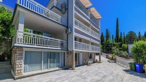 A multi-story building with balconies, a paved courtyard, and surrounding greenery. - Vacation apartment close to the beach in a quiet location in Crikvenica-Dramalj (Dramalj)