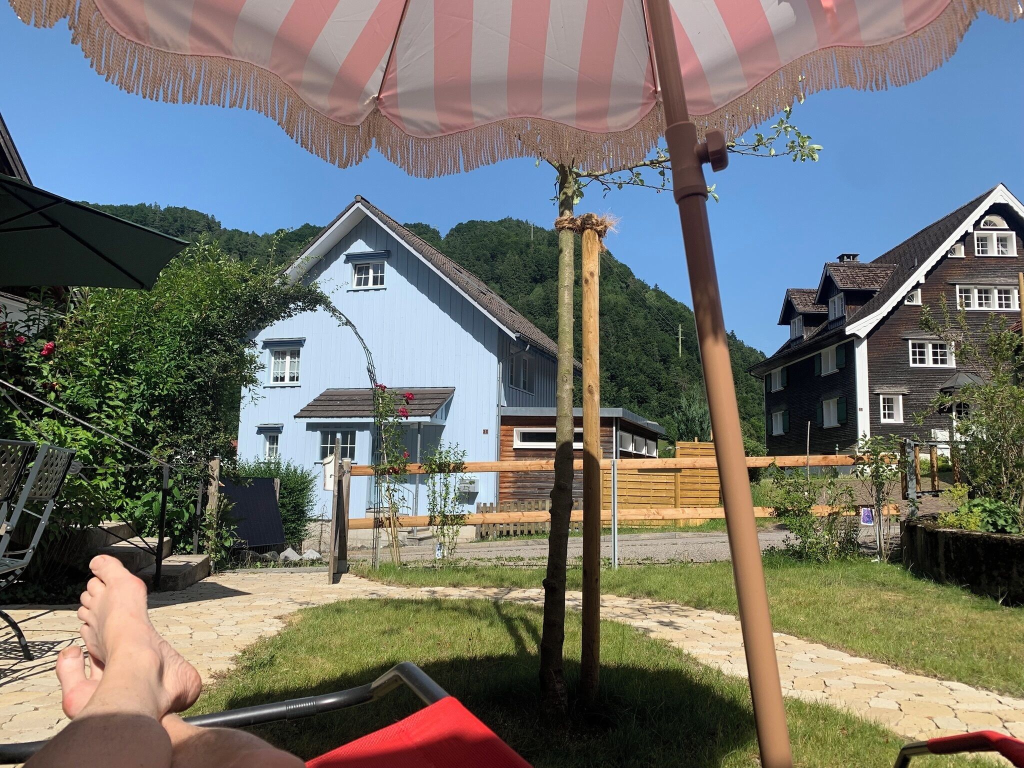 Un quartiere residenziale con una casa blu, un recinto in legno e un prato.