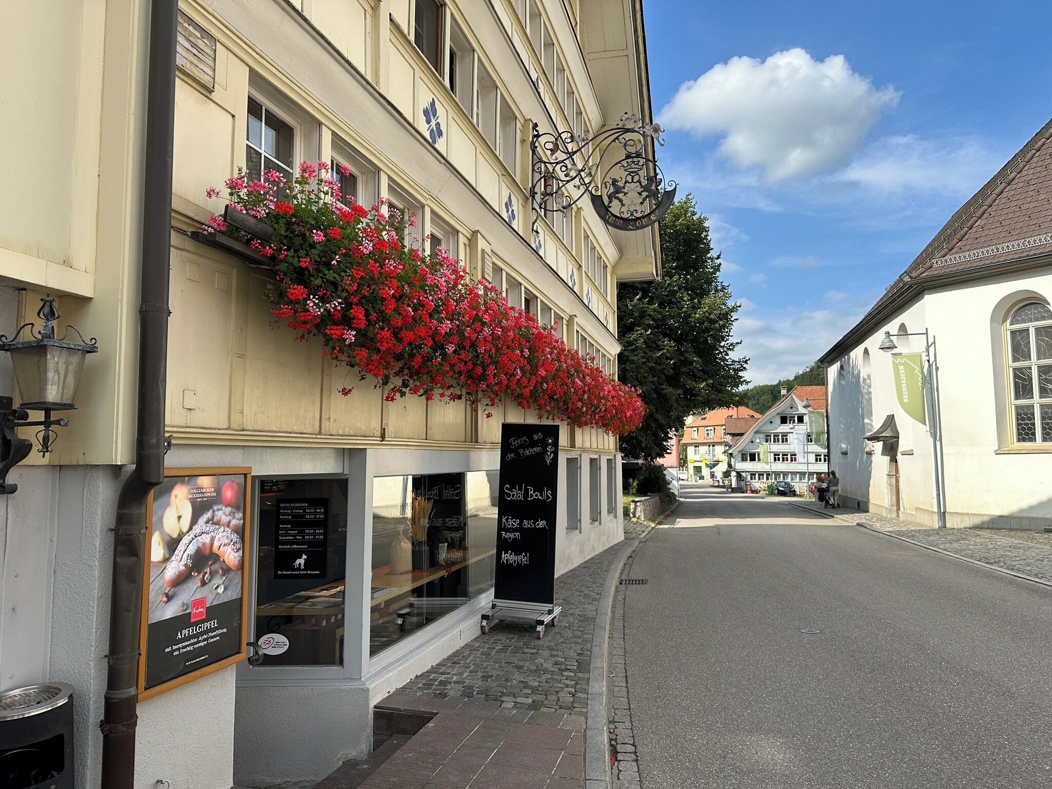 A building with a flower box, a signboard, and a street.