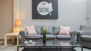 Ein modernes Wohnzimmer mit einem grauen Sofa, einem Glastisch und einem an der Wand befestigten Schild mit der Aufschrift 'MARTINI ROYAL CASTING'.