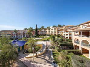 Ein Resort mit mehrstöckigen Gebäuden, einem zentralen Innenhof und Palmen.