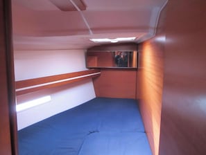 Ein schmales HĂ€uschen mit einem Einzelbett, einem kleinen Fenster und einem Spiegel.