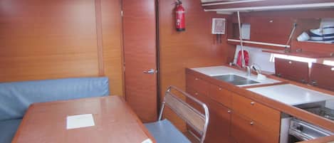A compact galley with a sink, stove, and a small seating area.