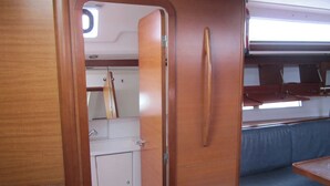 A compact interior with a wooden door, a small white cabinet, and a blue cushioned bench.