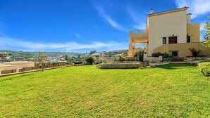 A modern two-story building with a flat roof, a stone retaining wall, and a well-maintained lawn. - Althea Villa | Private Pool, 5 Bedrooms & Garden Retreat Near Sandy Beach (Episkopi)
