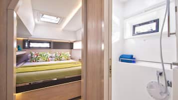 Un intérieur de camping-car compact comprenant un lit, une petite kitchenette et un espace douche.