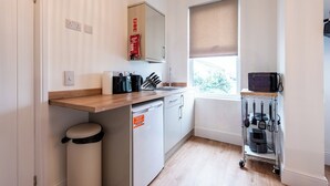 A compact kitchen with a sink, countertop, and a small dishwasher. - Glan Neigr by Guestz (Rhosneigr)
