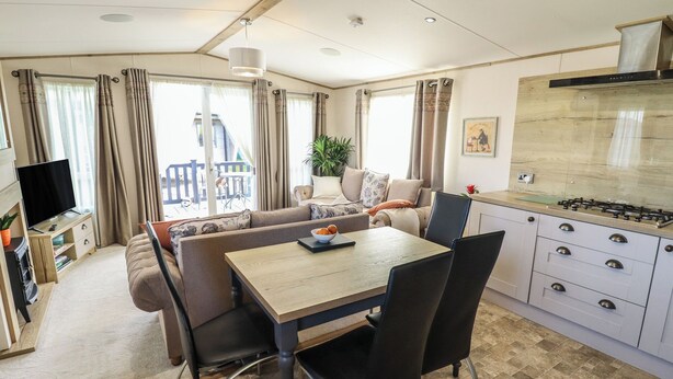 Une cuisine moderne équipée d’une cuisinière à gaz, d’une table à manger avec des chaises et d’un canapé, le tout dans une pièce lumineuse dotée de grandes fenêtres.
