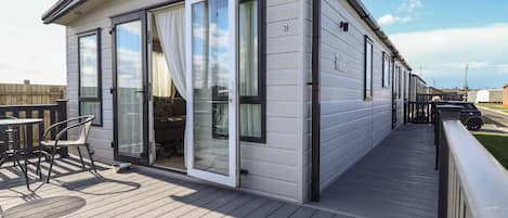 Een gelijkvloers gebouw met een terras, een schuifdeur en een klein zitgedeelte met stoelen.