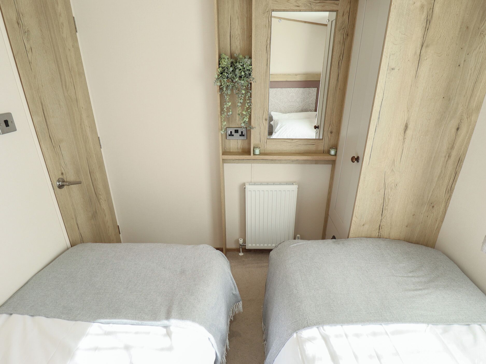 Una habitación con dos camas, un armario de madera, un espejo y un radiador.