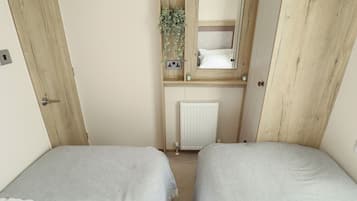 Una habitación con dos camas, un armario de madera, un espejo y un radiador.