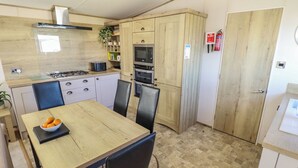Une cuisine compacte comprenant une table à manger, des chaises, un four à micro-ondes, un four et un extincteur.