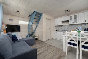 Un intérieur moderne comprenant un canapé, un téléviseur, un escalier, une cuisine et un coin repas.