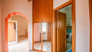 A hallway with a wooden door, a glass door, and a view into a kitchen area with a washing machine. - Phoebe House - Capestrano (Capestrano)