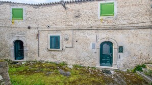 A building with three doors and two windows, each with green shutters. - Phoebe House - Capestrano (Capestrano)