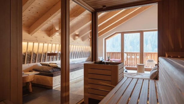 Un interior de madera con una cama en literas, un banco de madera y una mesita.
