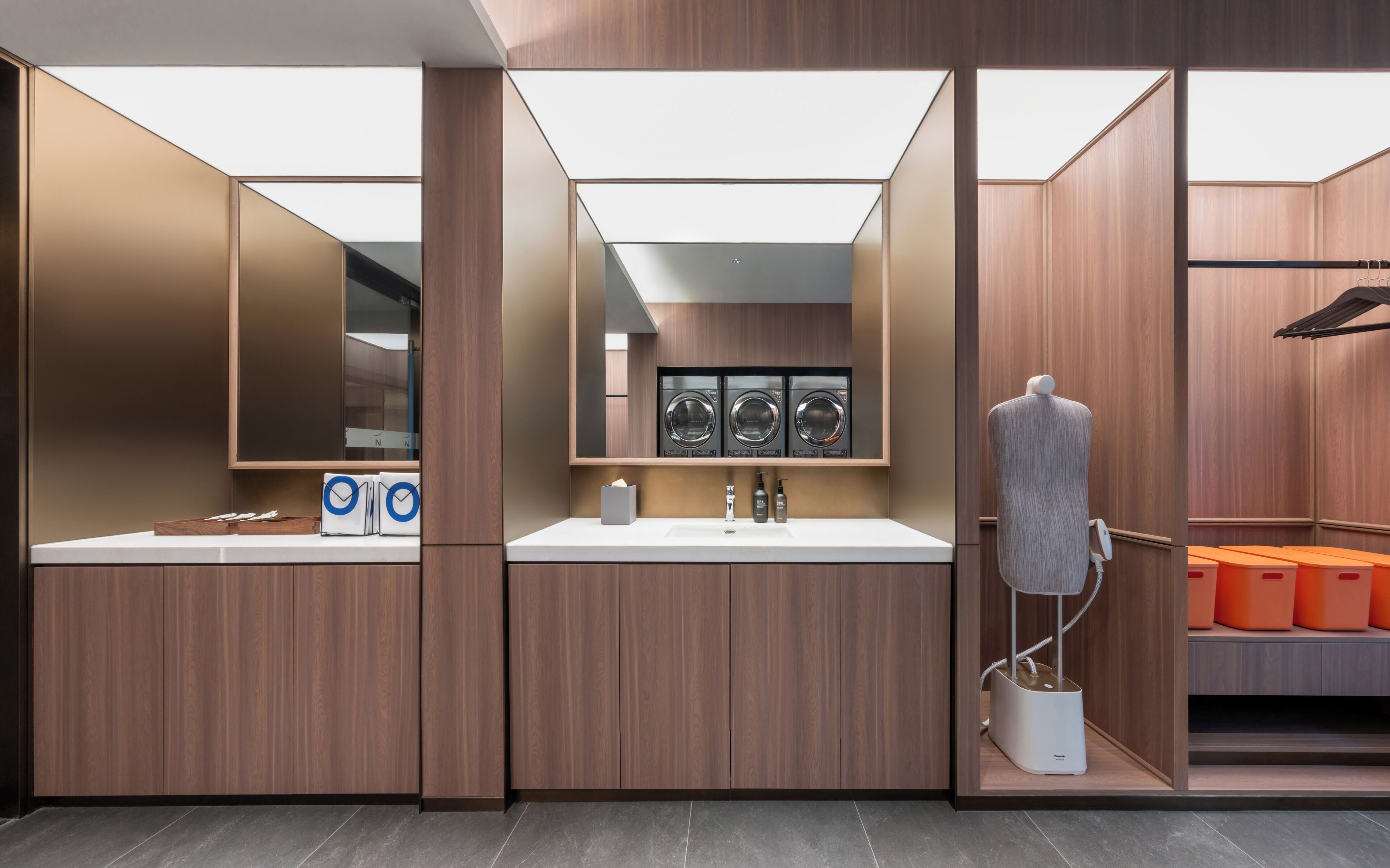 A modern bathroom with a vanity, three washing machines, and a drying station.