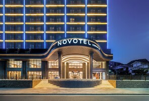 Un hotel moderno con una entrada destacada, varios pisos y una fachada bien iluminada.