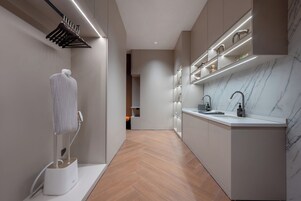 Una cocina moderna con encimera de mármol, toallero colgante y estanterías empotradas.