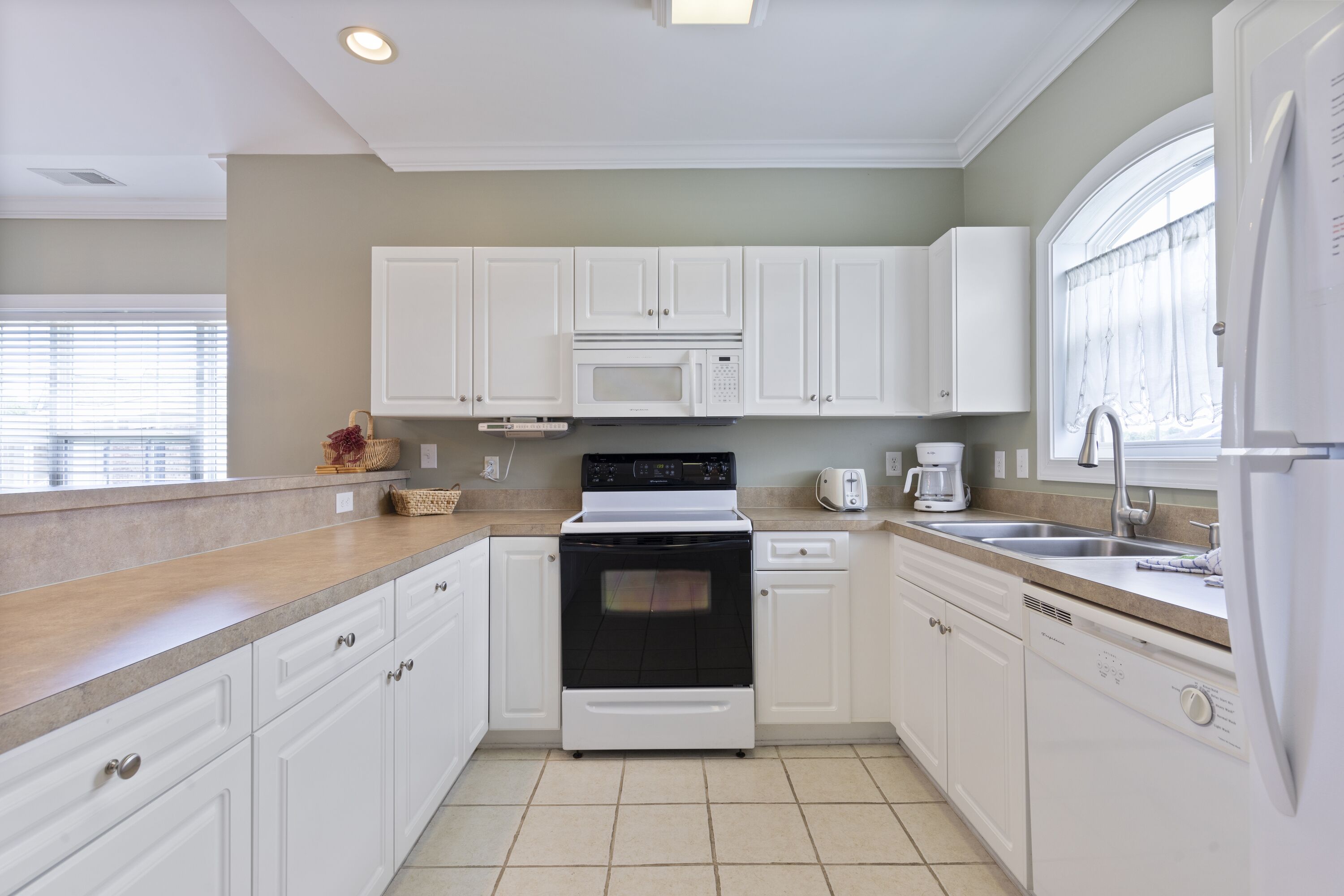 A kitchen with white cabinets, a microwave, an oven, a dishwasher, and a sink.
