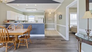 A spacious kitchen with a dining area, wooden chairs, a central island, and a chandelier. - Magnolia North 305 (Myrtle Beach)