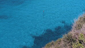 A coastal landscape with clear blue waters, rocky terrain, and a sandy beach. - Menorcan house with private pool, sea views, 10 minutes from the beach. (Cala en Porter)