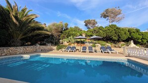 A swimming pool with lounge chairs and umbrellas, surrounded by stone walls and greenery. - Menorcan house with private pool, sea views, 10 minutes from the beach. (Cala en Porter)