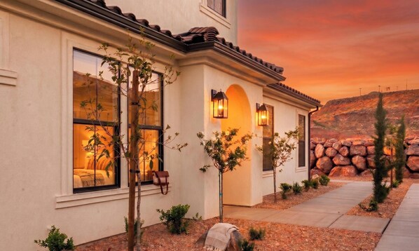 A two-story house with large windows, a stone wall, and a landscaped garden. - Southern Utah Wonder... Under the Sage Arches. Your family will be close to everything from parks to town when you stay at this centrally-located house. (Washington)