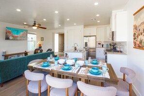 A dining area with a wooden table set for six, surrounded by chairs, in a modern kitchen with white cabinets and stainless steel appliances. - Southern Utah Wonder... Under the Sage Arches. Your family will be close to everything from parks to town when you stay at this centrally-located house. (Washington)